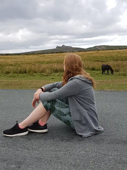 Mädchen beobachtet Wildpferde im Dartmoor