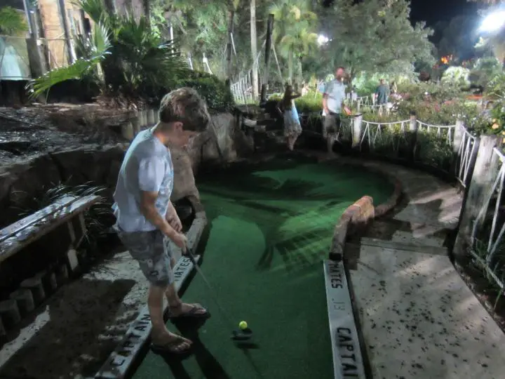 Kind spielt Minigolf im Pirates Cove Adventure Golf in Orlando, Florida