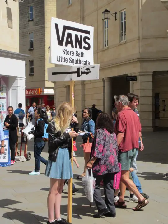 Mitten auf der Straße von Bath halten Studenten Werbeschilder - ein schöner Job bei schönem Wetter