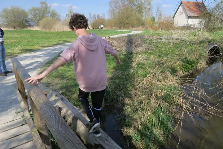 Kind balanciert im Wackelwald auf einem Baumstamm