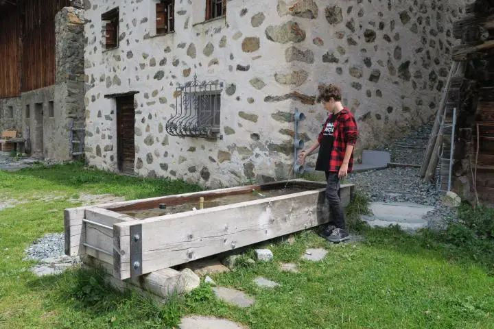 Kurze Rast am Brunnen, Alpflix, Graubünden mit Kindern