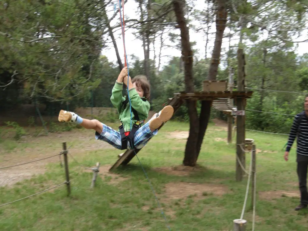 Kind auf eine Zip-Line im Hochseilgarten am Lac de la Cavayère