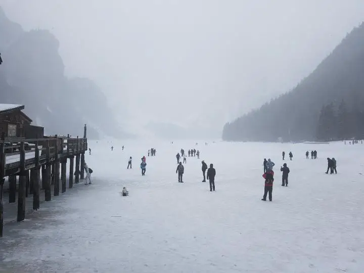 Menschen gehen auf dem zugefrorenen Pragser Wildsee spazieren